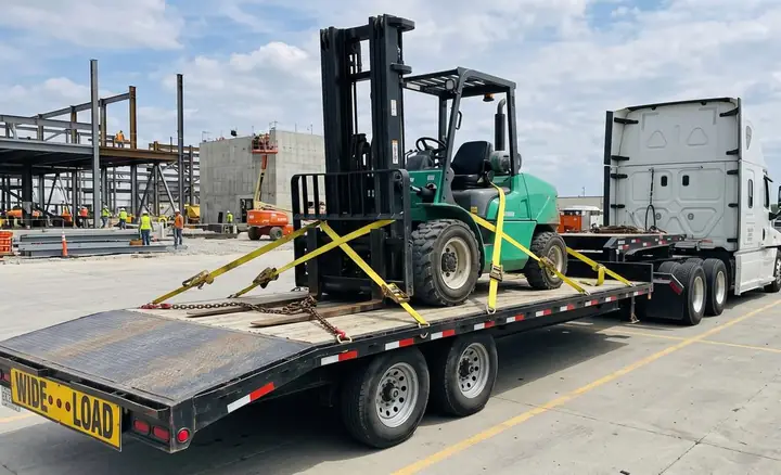 A skid steer strapped onto a heavy-duty flatbed trailer for transport